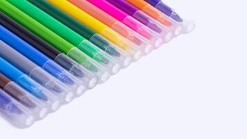 Colorful markers neatly arranged on white background with copy space. Set of rainbow felt-tip pens for kids art, drawing, coloring, school supplies, stationery, and creative education. photo