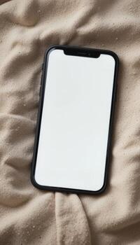 Blank Smartphone Screen . A modern smartphone with a large blank white display lying on a fabric surface, ready for mobile app or UI presentation. photo
