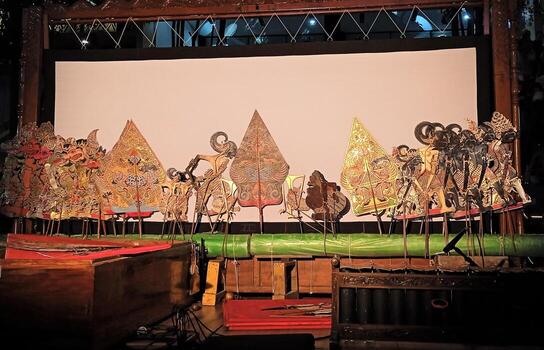 Wayang kulit are neatly arranged in front of a white screen in a traditional Javanese performance, played all night long by the puppeteer or dalang accompanied by gamelan photo