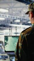 vertikal militär data Centrum specialist använder sig av radar programvara på bärbar dator till Kolla på för fiende hot. armén soldat i data Centrum skannar misstänkt aktivitet till upptäcka, detektera faror använder sig av anteckningsbok, kamera b video