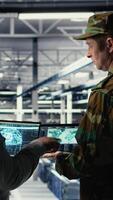 Vertical Military commander and female programmer in data center tracking coordinates using notebook software. Soldier and african american woman in server hub analyzing reconnaissance data, camera A video