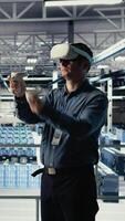 Vertical Data center system administrator uses virtual reality tech, improving AI rigs processing speed. Man in server farm wearing VR goggles to provide support for artificial intelligence workloads, camera A video