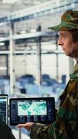Vertical Military commander and female programmer in data center tracking coordinates using notebook software. Soldier and african american woman in server hub analyzing reconnaissance data, camera B video