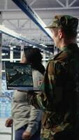 Vertical Military engineer in data center tracking satellite coordinates using laptop interface. Soldier in server room analyzing reconnaissance data through satellite imaging systems, camera A video