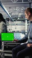 Vertical Data center IT experts investigate AI configurations using green screen laptop, making adjustments. Server hub engineers check deep learning errors on chroma key notebook, camera A video