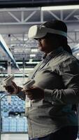 Vertical Data center technician using virtual reality, improving AI rigs processing speed. Server hub IT expert using VR headset to manage gear providing support for artificial intelligence workloads, camera A video