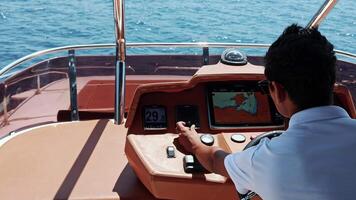 fartyg kapten användningar datoriserad Diagram medan navigerande Yacht, båt. interiör se av kontrollera panel och olika elektronisk enheter. över axel skott i de bakgrund av de instrumentbräda video