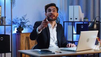 I choose you. Young Indian businessman programmer software developer working on office laptop pointing to camera, looking with happy expression, making choice, showing direction. Arab freelancer man video