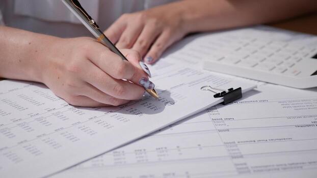 A closeup image depicts hands diligently writing on financial forms, with a calculator close by for quick calculations photo