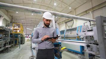 handledare övervakning produktion linje använder sig av digital läsplatta i fönster fabrik video
