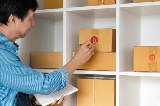 E-commerce professional checking inventory boxes on a shelf with a notepad. photo