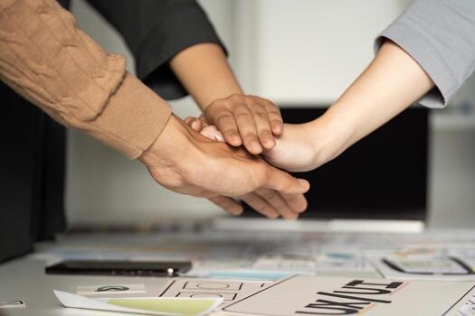 Collaborative Teamwork in UX UI Design Process with Hands Stacked Over Design Documents and Digital Devices photo