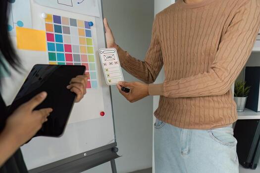 Designers Collaborating on UX UI Concepts with Digital Tablet and Wireframe Sketches in Modern Office Setting photo