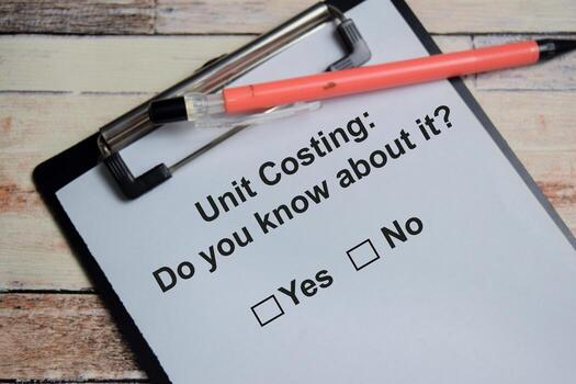 Unit costing do you know about it write on clipboard isolated on Wooden Table. A person is answering question concept photo