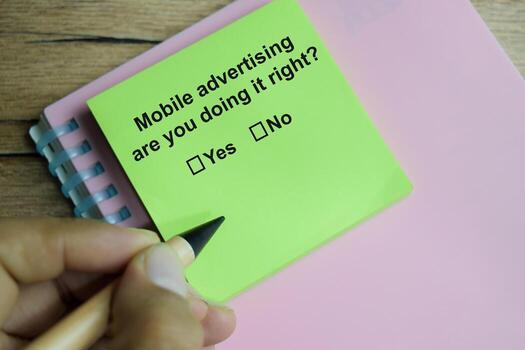 Mobile advertising are you doing it right write on sticky notes isolated on Wooden Table. A person is answering question concept photo