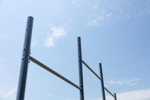 Vertical bars create a workout station for users in a serene park setting under a bright sky with few clouds photo