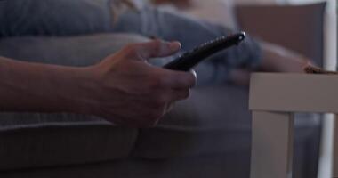 beskära man liggande på soffa och använder sig av avlägsen kontrollera video