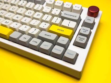 Mechanical keyboard with bright Enter key yellow background, minimalism, keyboard buttons. A keyboard with a yellow key on the bottom left photo