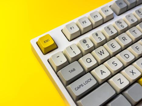 White mechanical keyboard with bright Esc key on bright yellow background keyboard with a yellow key on the bottom left photo