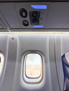 Airplane window view with visible engine and control panel above. Passenger environment, aviation design, and inflight atmosphere before departure. photo