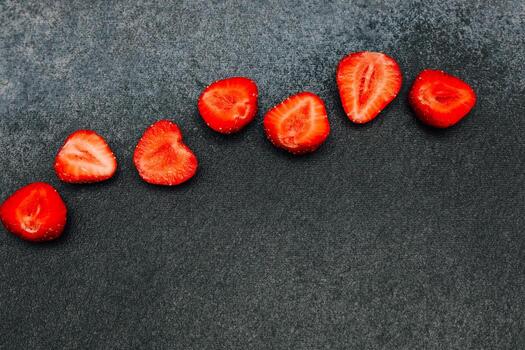 rebanado fresas arreglado en un oscuro superficie creando un visualmente atractivo modelo foto