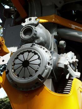 A yellow and grey engine with a black wheel. The wheel is missing. The engine is in a factory photo