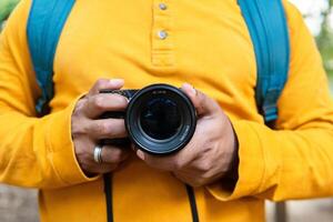 fotógrafo vistiendo amarillo camisa, que lleva cámara y mochila, excursionismo mediante lozano bosque camino, experimentando desierto conexión foto
