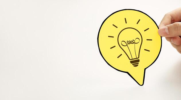 Hand holding a circle paper with light bulb icon. Represents new idea generation, design thinking, creative process and complex problem solving, with copy space photo