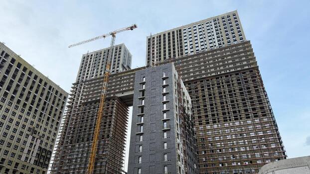 Construction site of two tall residential buildings under development, with scaffolding and crane, showcasing the modern building process and urban architecture in progress photo