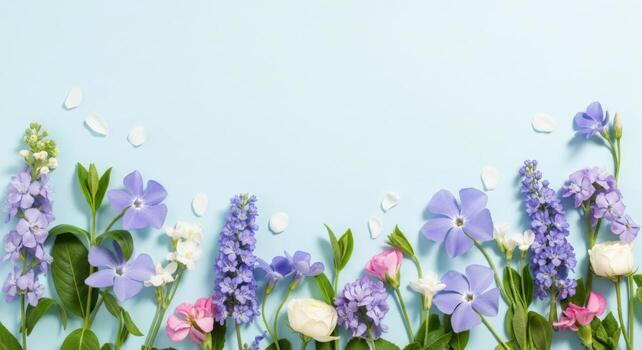 Delicate spring flowers creating a border on a light blue backdrop photo