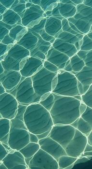 Sunlight patterns on the sandy seabed beneath clear turquoise water photo