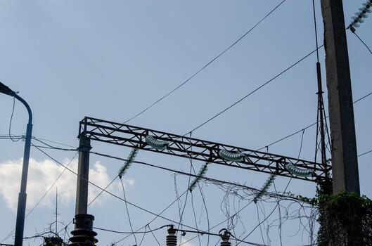 A power line with a green and white wire. The sky is blue and clear. The power line is high above the ground photo