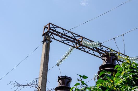 A power line pole with a metal structure on top and a bunch of glass bottles hanging from it photo