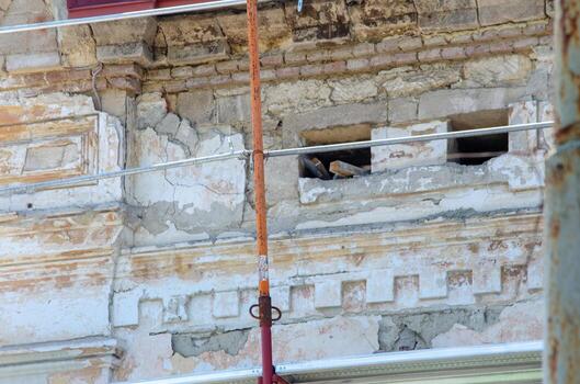 A building with a hole in the wall and a bird in it. The bird is sitting on a ledge photo