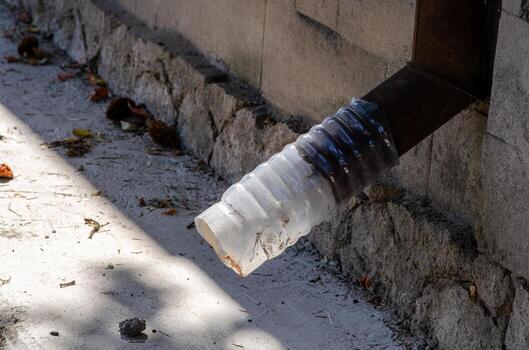 A pipe is covered with plastic and is attached to a wall. The pipe is dirty and has a rust color photo