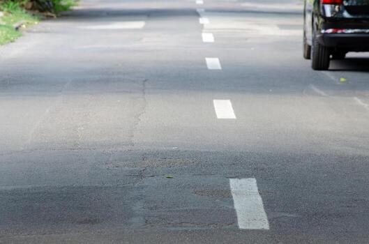 A car is driving down a road with a white line in the middle. The road is empty and the car is the only thing visible photo