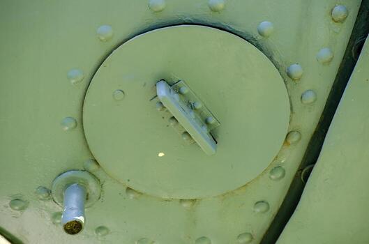 A green metal object with a hole in the middle. The hole is surrounded by a lot of small holes photo
