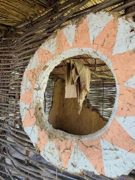 A round window with a white and orange design. The window is open and a piece of cloth is hanging from it photo