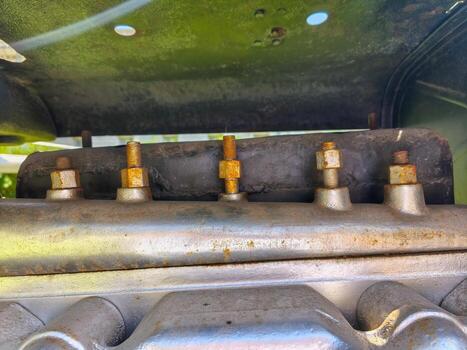 A rusty engine with bolts on it. The engine is on the ground photo