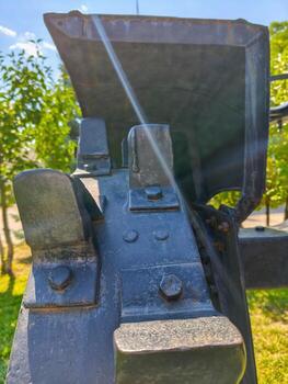 A black and grey object with a shiny surface. The shiny surface is reflecting sunlight. The object is surrounded by trees photo