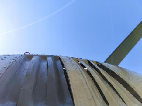 A plane with a large propeller on the side. The propeller is covered in rust, giving the plane a worn and aged appearance. The sky above the plane is clear and blue, creating a sense of calm photo