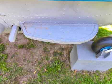 A grey airplane with a grey step on the side. The step is on the side of the plane and is made of metal photo