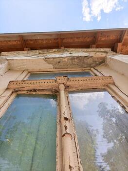 The window is old and has a lot of damage. The wood is rotten and the glass is cracked. The view outside is obscured by the window photo