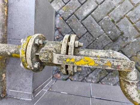 A rusty pipe with a yellow handle. The pipe is dirty and has a yellow handle photo