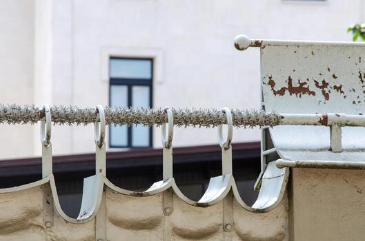 A white fence with a black metal bar on it. The bar is covered in rust and has a foreign language written on it photo