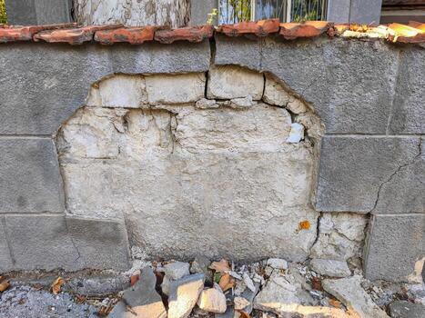 A wall with a hole in it and a brick missing. The wall is made of cement blocks photo