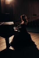 elegancia mujer a el piano en un negro vestido foto