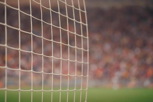 Soccer field goal net close up with blurred football stadium and crowd in background creating exciting sports atmosphere during match photo