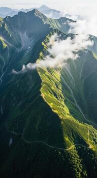 Sunlight illuminates a lush green mountain range with clouds photo
