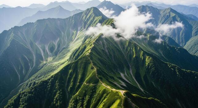 Lush green mountain range with a winding trail and clouds photo
